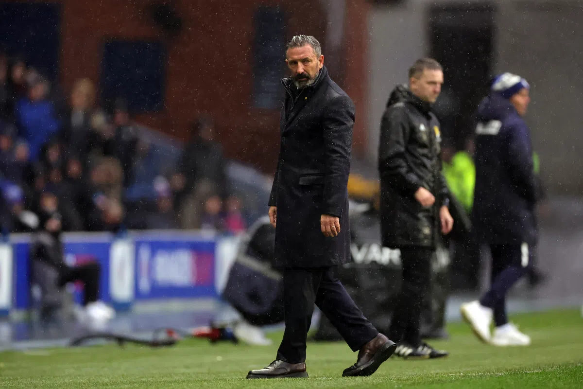 Derek McInnes staat langs de zijlijn op een nat voetbalveld.