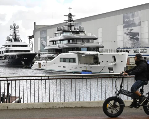 Jachten liggen bij een scheepswerf van Damen, met grote werfgebouwen op de achtergrond.