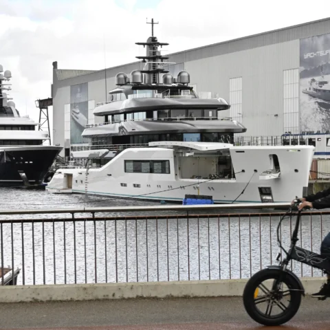 Jachten liggen bij een scheepswerf van Damen, met grote werfgebouwen op de achtergrond.