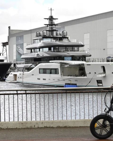 Jachten liggen bij een scheepswerf van Damen, met grote werfgebouwen op de achtergrond.