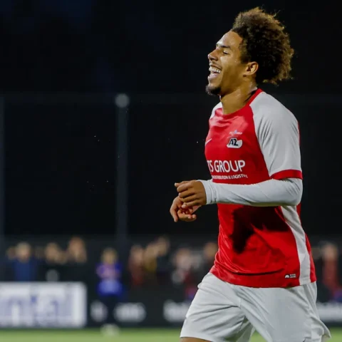 AZ-speler in rood-wit juicht tijdens een avondwedstrijd.