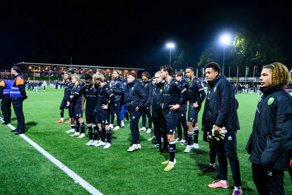 ADO Den Haag-spelers en staf staan na afloop van de wedstrijd op het veld bij kunstlicht.