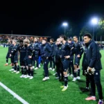 ADO Den Haag-spelers en staf staan na afloop van de wedstrijd op het veld bij kunstlicht.