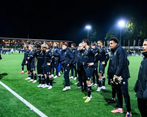 ADO Den Haag-spelers en staf staan na afloop van de wedstrijd op het veld bij kunstlicht.