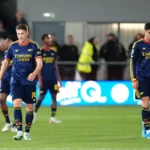 Arsenal-spelers lopen teleurgesteld op het veld tijdens een wedstrijd.