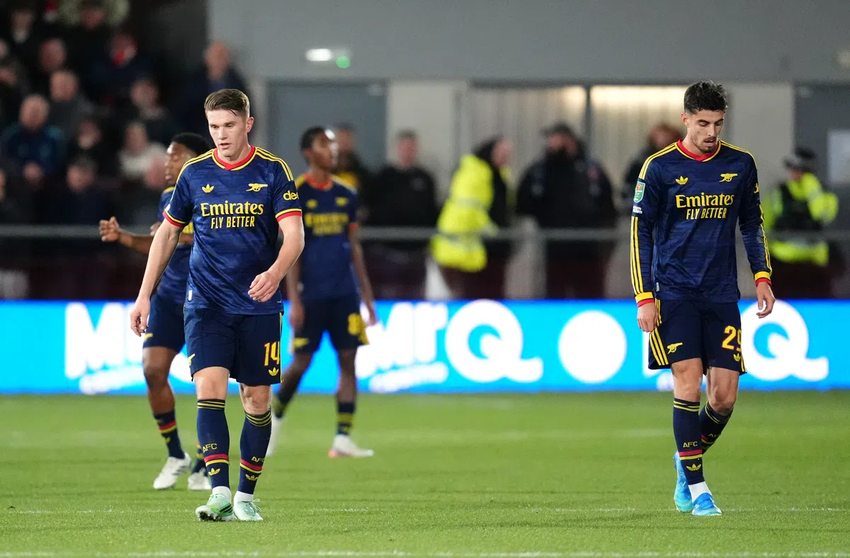 Arsenal-spelers lopen teleurgesteld op het veld tijdens een wedstrijd.