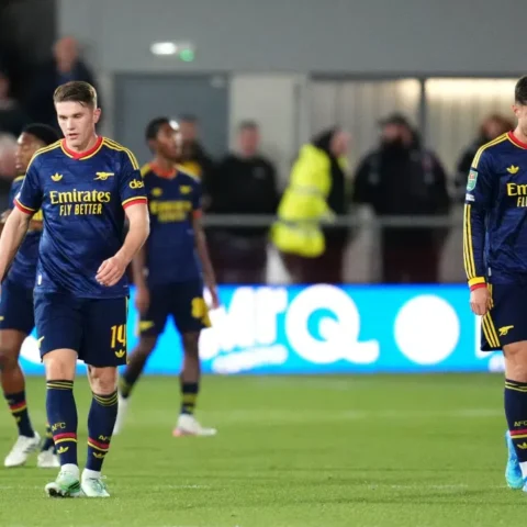Arsenal-spelers lopen teleurgesteld op het veld tijdens een wedstrijd.