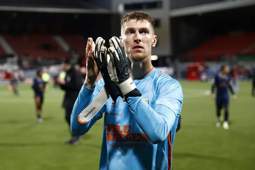 Mark Spenkelink in een lichtblauw keepersshirt klapt op het veld na de wedstrijd.