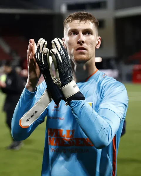 Mark Spenkelink in een lichtblauw keepersshirt klapt op het veld na de wedstrijd.