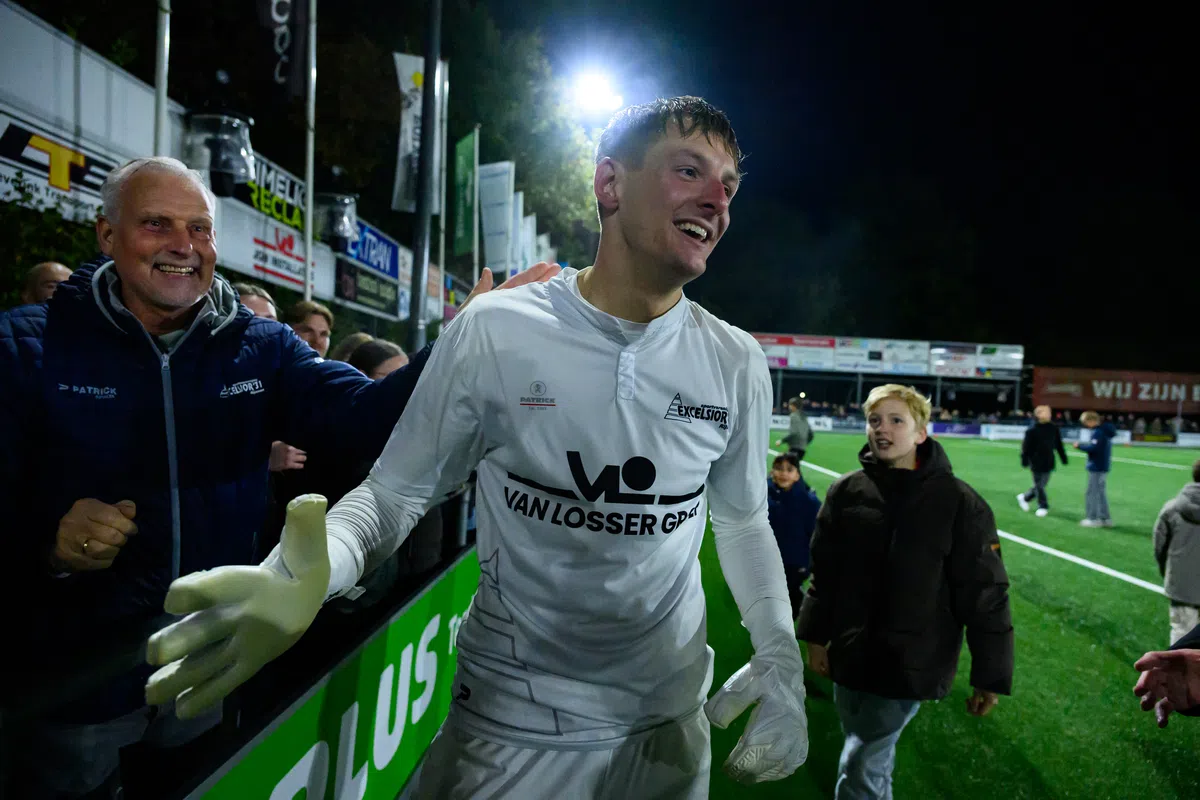 Kevin Reimink in een wit keepershirt na de wedstrijd, lachend langs het veld terwijl supporters hem feliciteren.