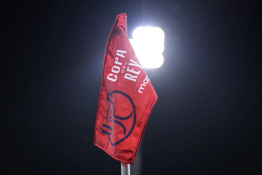 Rode cornervlag met Copa del Rey-opdruk in een stadion bij felle stadionlampen.