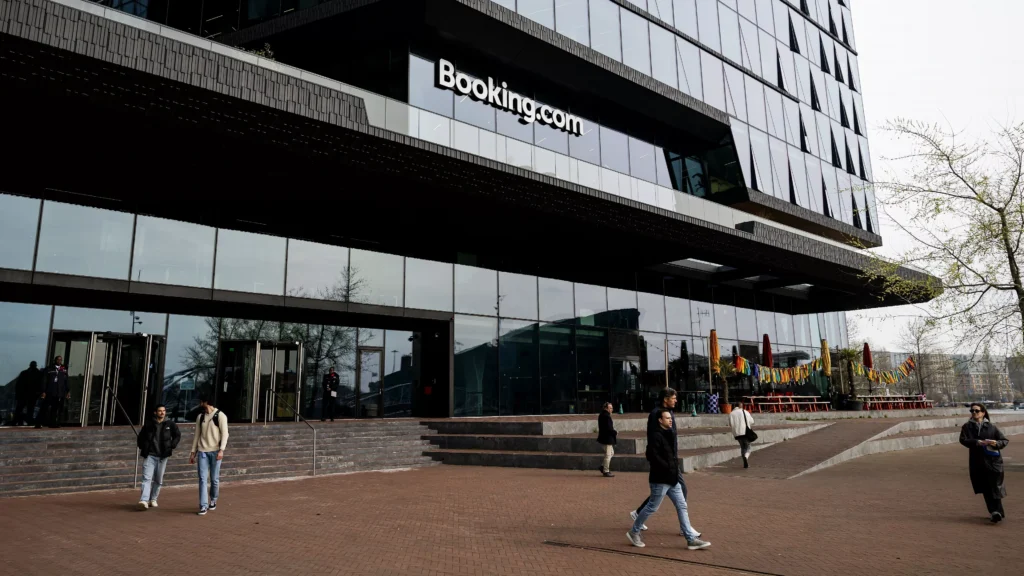 Buitenaanzicht van het Booking.com-hoofdkantoor met mensen op het plein ervoor.