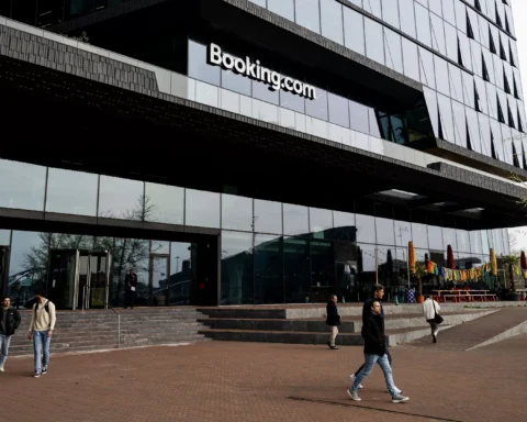 Buitenaanzicht van het Booking.com-hoofdkantoor met mensen op het plein ervoor.