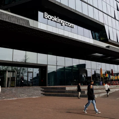 Buitenaanzicht van het Booking.com-hoofdkantoor met mensen op het plein ervoor.
