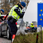 Nederlandse politie controleert voertuigen bij een grenscontrole, naast een bord met ‘Nederland’.