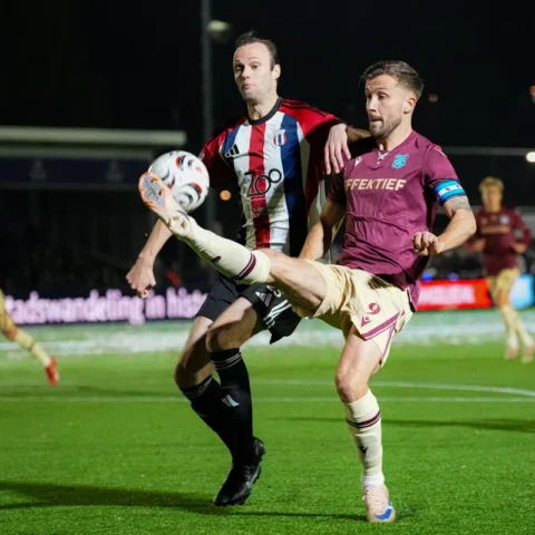 Voetballers van SC Heerenveen en Excelsior Maassluis vechten om de bal op kunstgras bij nacht.