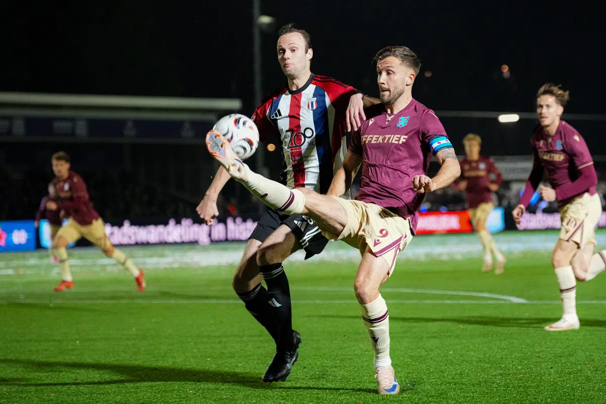 Voetballers van SC Heerenveen en Excelsior Maassluis vechten om de bal op kunstgras bij nacht.
