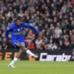 Chelsea-speler schiet de bal tijdens een wedstrijd in een vol stadion.