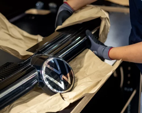 Werknemer verpakt een Volkswagen-grille met het VW-logo in een werkplaats.