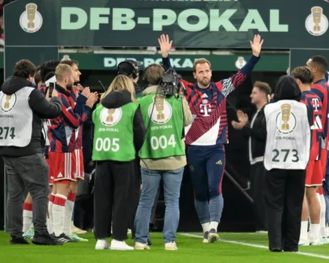 Harry Kane zwaait met beide handen terwijl hij met Bayern München-spelers en staf door een DFB-Pokal erehaag loopt.