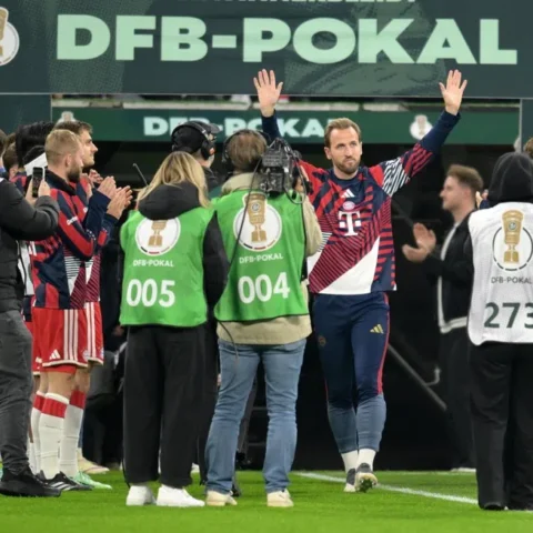 Harry Kane zwaait met beide handen terwijl hij met Bayern München-spelers en staf door een DFB-Pokal erehaag loopt.