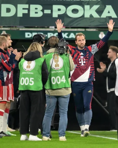 Harry Kane zwaait met beide handen terwijl hij met Bayern München-spelers en staf door een DFB-Pokal erehaag loopt.