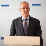 Klaas Knot spreekt bij een spreekgestoelte voor een achtergrond met De Nederlandsche Bank-logo's.