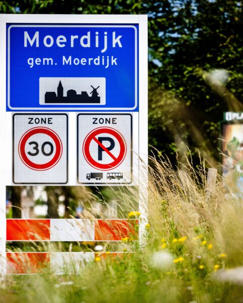 Bord bij de ingang van Moerdijk met plaatsnaam, snelheidszone en parkeerverbod.
