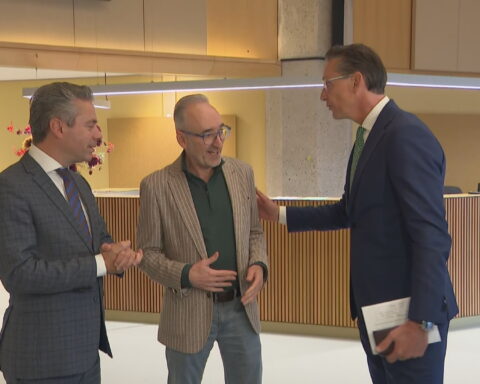 Drie mannen staan met elkaar te praten in een overheidsgebouw.