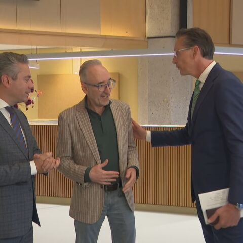 Drie mannen staan met elkaar te praten in een overheidsgebouw.