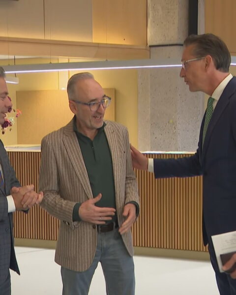 Drie mannen staan met elkaar te praten in een overheidsgebouw.