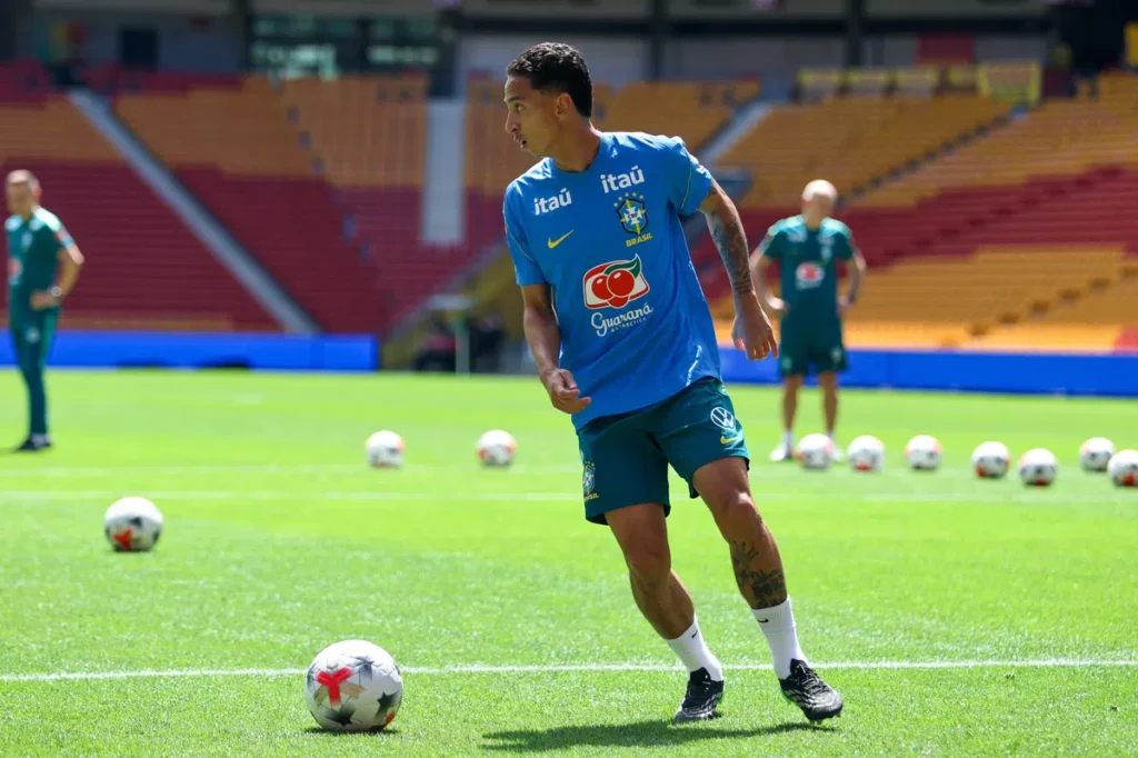 Brazilian footballer in training kit on a pitch during a team session.