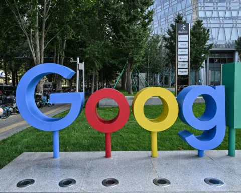 Groot Google-logo bij een kantoorcampus met bomen en een moderne glazen gevel op de achtergrond.