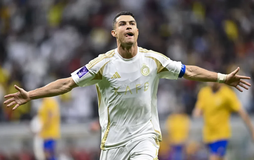 Cristiano Ronaldo viert een doelpunt in het wit-gouden tenue van Al Nassr met uitgestrekte armen.