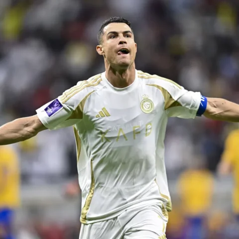 Cristiano Ronaldo viert een doelpunt in het wit-gouden tenue van Al Nassr met uitgestrekte armen.