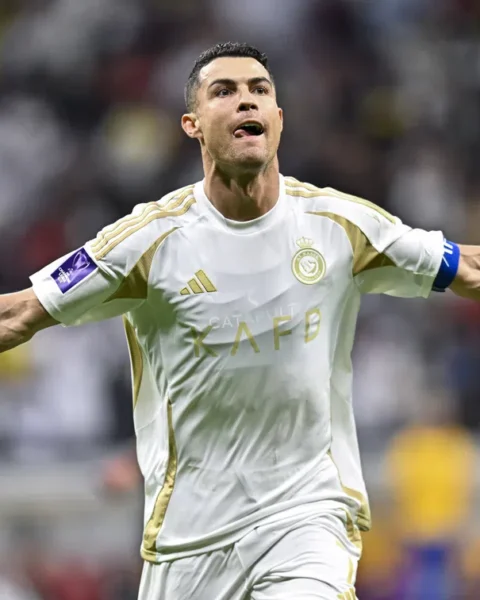 Cristiano Ronaldo viert een doelpunt in het wit-gouden tenue van Al Nassr met uitgestrekte armen.