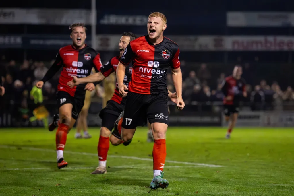 De Treffers-spelers vieren een doelpunt op het veld tijdens een avondwedstrijd.