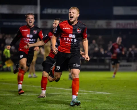 De Treffers-spelers vieren een doelpunt op het veld tijdens een avondwedstrijd.