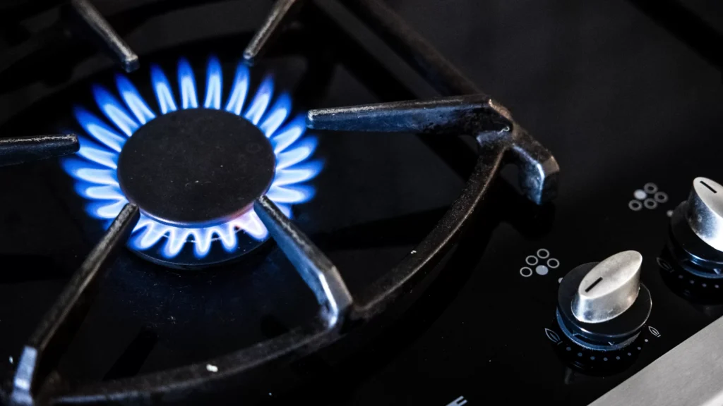 Blauwe gasvlam brandt op een gasfornuis.