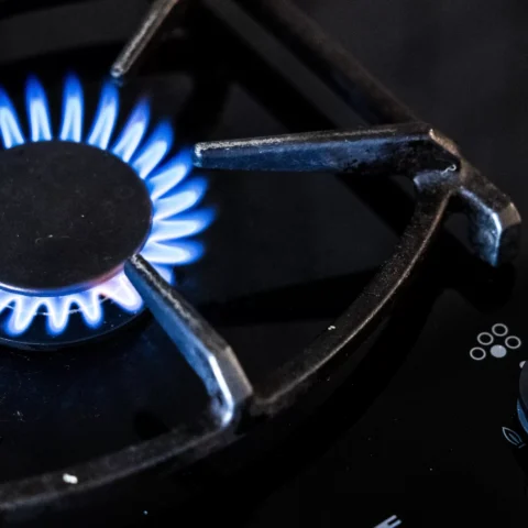 Blauwe gasvlam brandt op een gasfornuis.