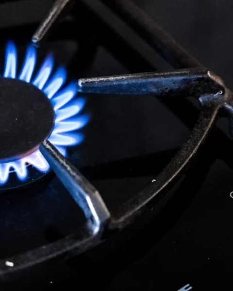 Blauwe gasvlam brandt op een gasfornuis.