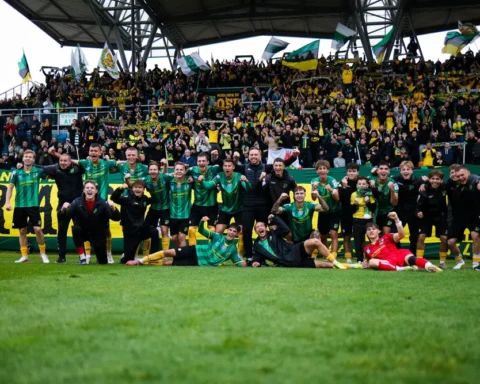 Voetballers van een team vieren met supporters in een stadion na een wedstrijd.