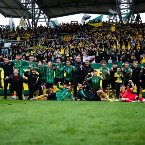 Voetballers van een team vieren met supporters in een stadion na een wedstrijd.