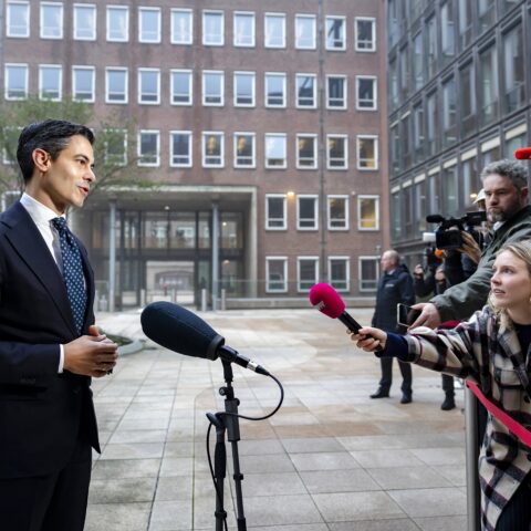Rob Jetten spreekt buiten een gebouw met journalisten en camera’s om zich heen.