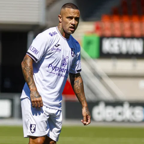 Radja Nainggolan staat in een wit voetbalshirt op het veld.