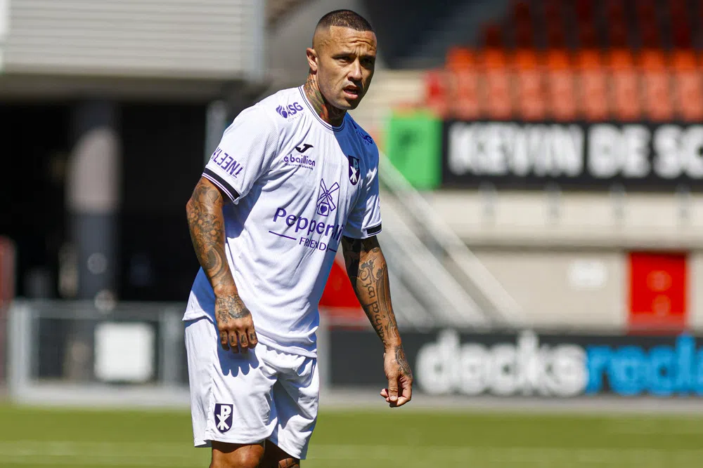 Radja Nainggolan staat in een wit voetbalshirt op het veld.