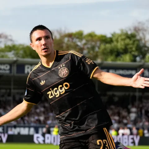 Ajax-speler in zwart uittenue juicht op het veld tijdens een wedstrijd.