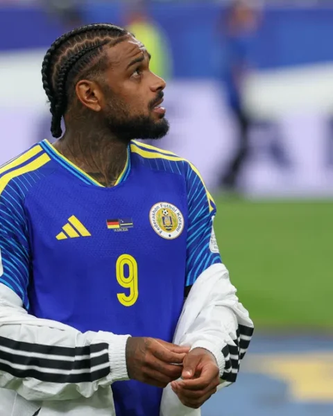 Curaçaose voetballer in blauw nationaal shirt kijkt omhoog op het veld.