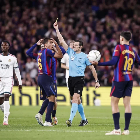 Scheidsrechter met een gele kaart tussen spelers tijdens een La Liga-wedstrijd.