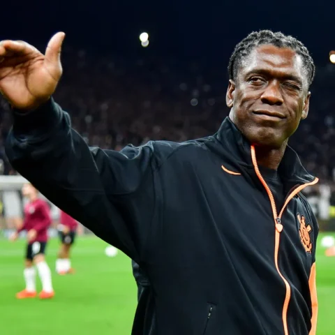 Clarence Seedorf steekt zijn hand op langs het veld voor een voetbalwedstrijd.